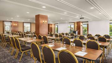 A conference room with multiple tables and chairs, equipped with nameplates and water glasses.