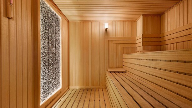 Una sauna con bancos de madera y pared de piedra.