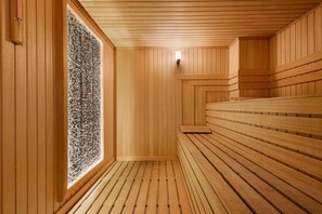 Una sauna con bancos de madera y pared de piedra.