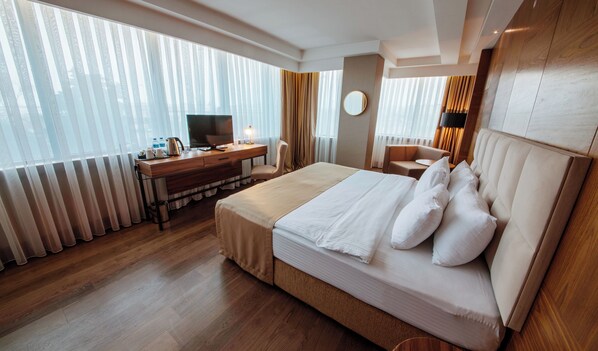 A hotel room with a large bed, a desk with a TV, and a chair. - Ramada Plaza by Wyndham Samsun (Samsun)