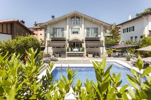 Una piscina al aire libre, sombrillas, sillones reclinables de piscina