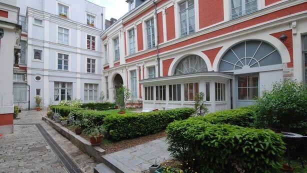 A courtyard with a cobblestone path, neatly trimmed hedges, and a variety of potted plants. - Lille A Part - Gites Urbains (Lille)