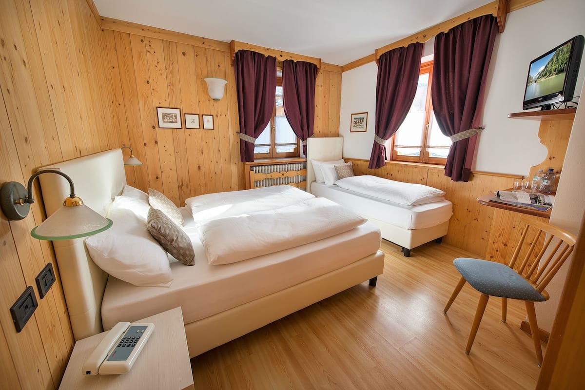 Une chambre d’hôtel avec deux lits, un bureau, une chaise et un téléviseur.
