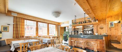 A cozy wooden interior with a bar area, wooden tables, and benches.