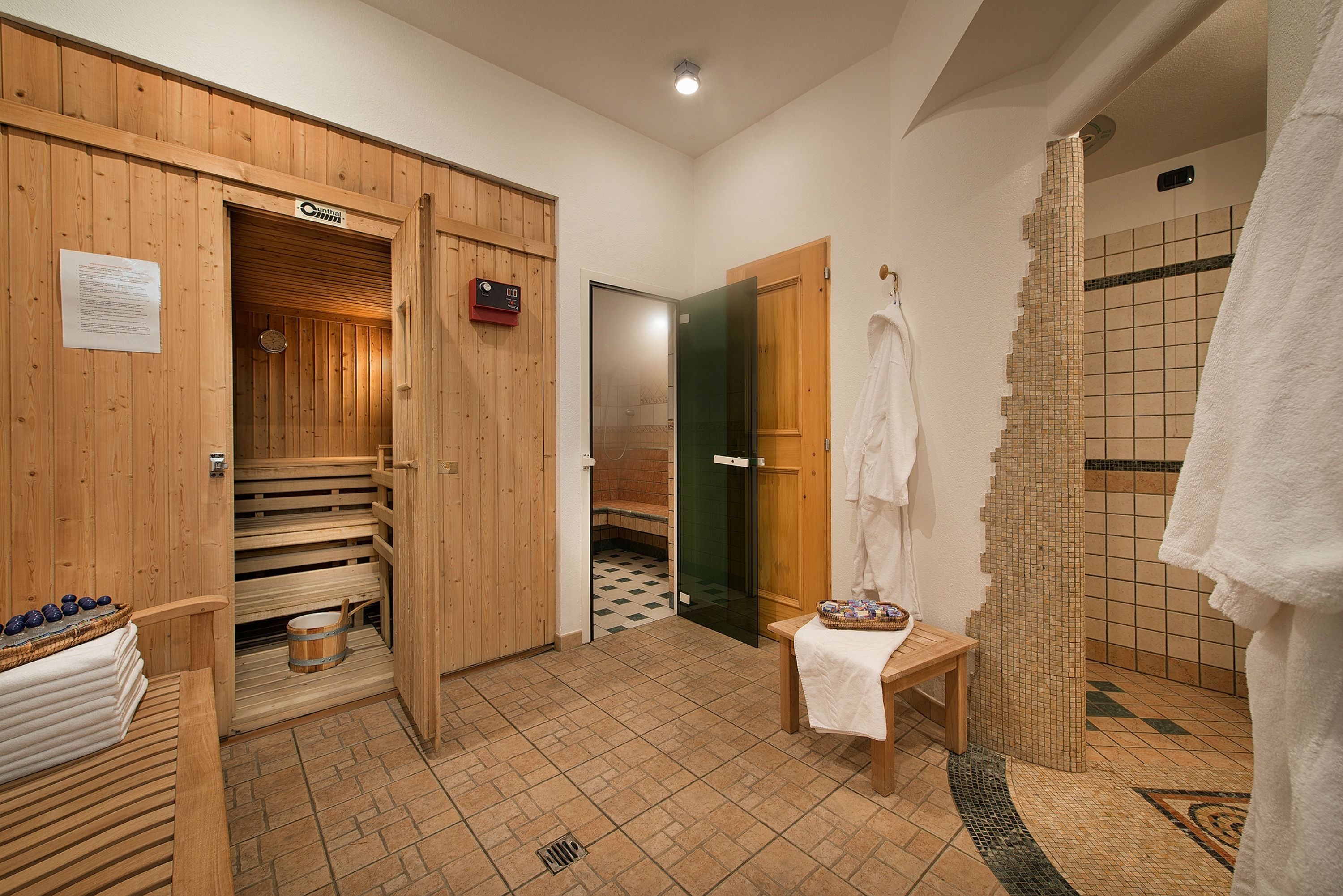 A sauna room with wooden benches, a bench with a towel, a bucket, and a small table with a towel.