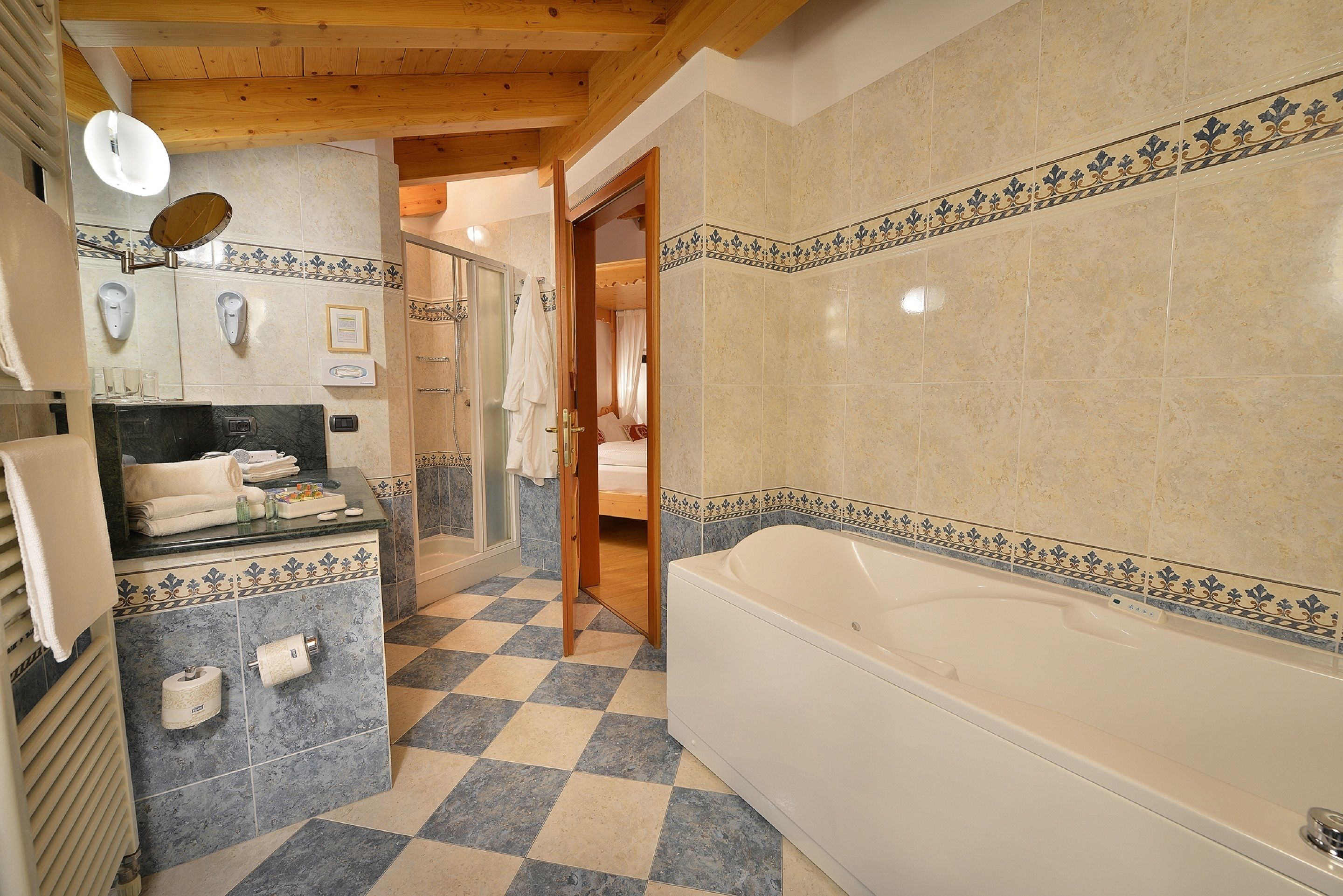 A bathroom with a checkered floor, a bathtub, a mirror, and a towel rack.