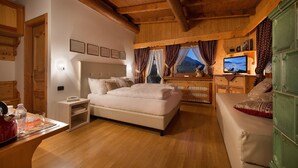 Een slaapkamer met een bed, een televisie, houten meubels en een raam met gordijnen.