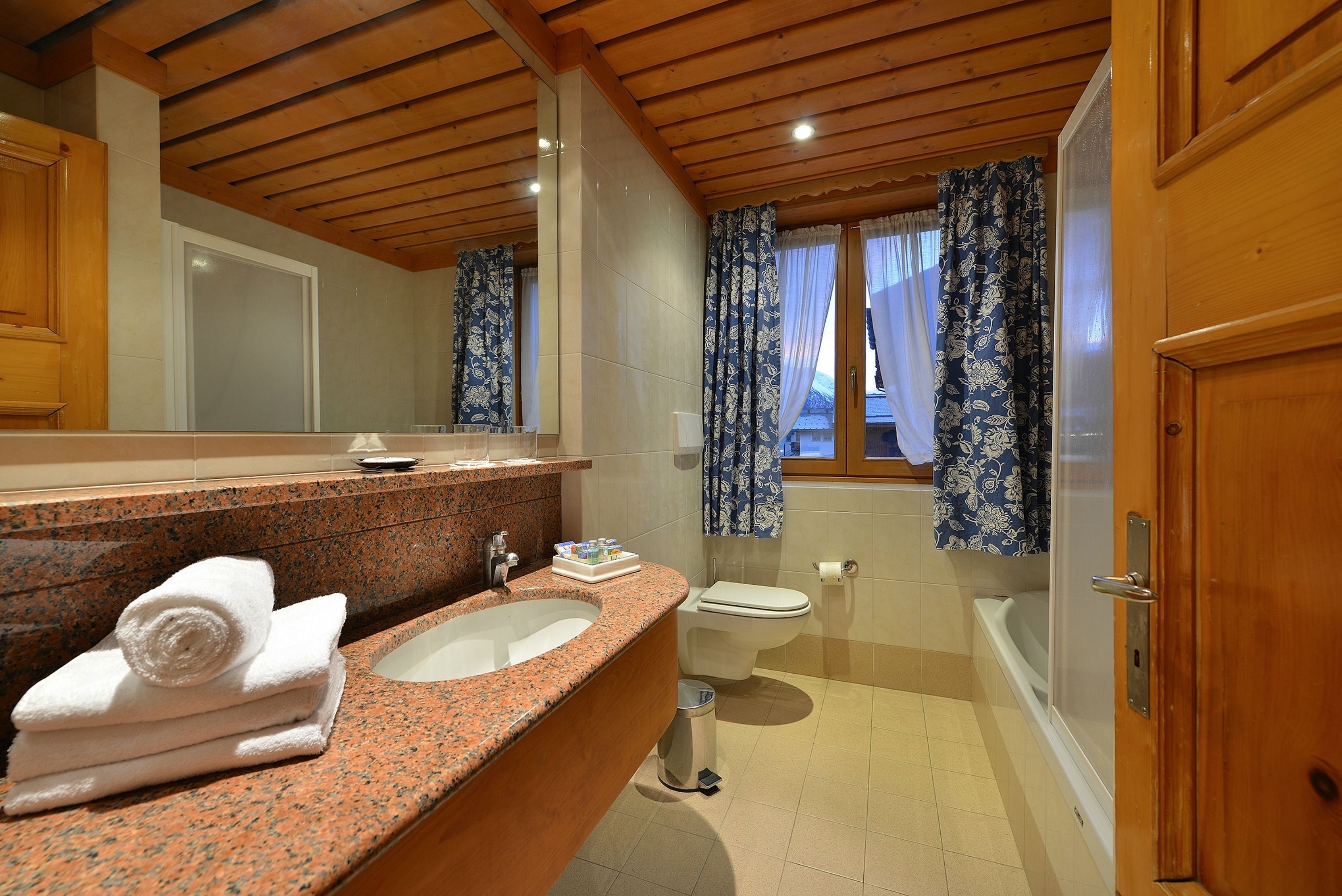 Ein Badezimmer mit Granitplatte, Waschbecken, Toilette und Badewanne.