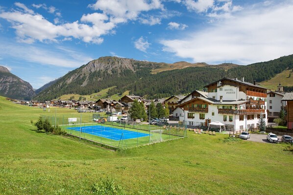 Un hôtel doté d’un court de tennis, entouré de montagnes et de verdure.