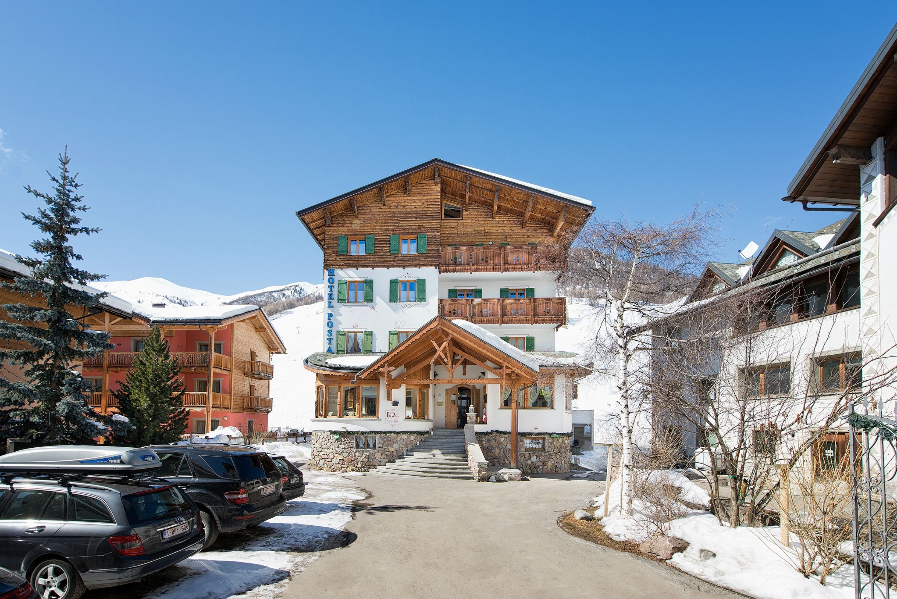 A multi-story building with a wooden facade, a balcony, and a staircase leading to the entrance.