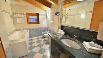 A bathroom with a checkered floor, a bathtub, a sink, and a large mirror.