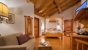 Een knus interieur met een houten plafond, een hemelbed, een bank en een klein tafeltje met een tijdschrift.