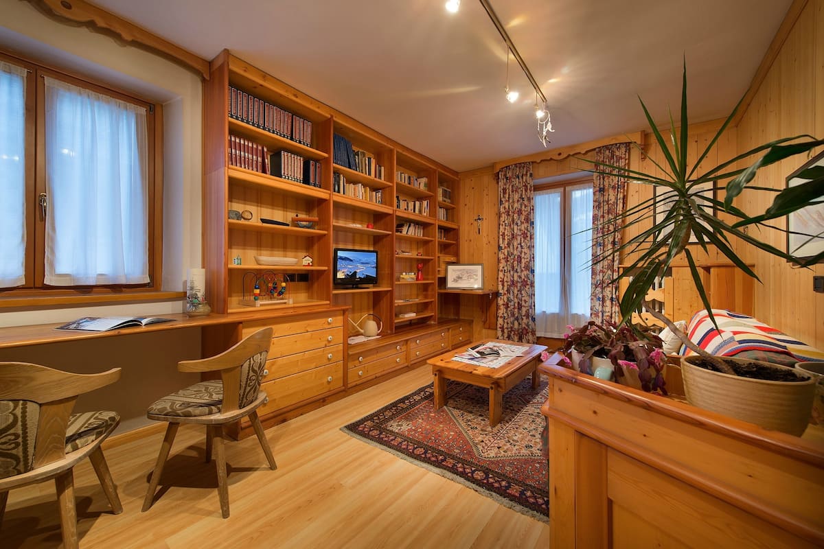 Un salon chaleureux, avec des meubles en bois, une bibliothèque, un téléviseur et une grande plante.