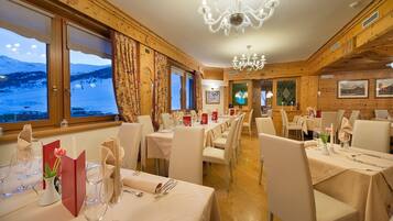 A dining area with wooden walls, chandeliers, and tables set for a meal.