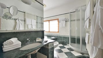 Un baño con piso a cuadros, dos lavamanos, cabina de ducha de vidrio y un espejo grande.