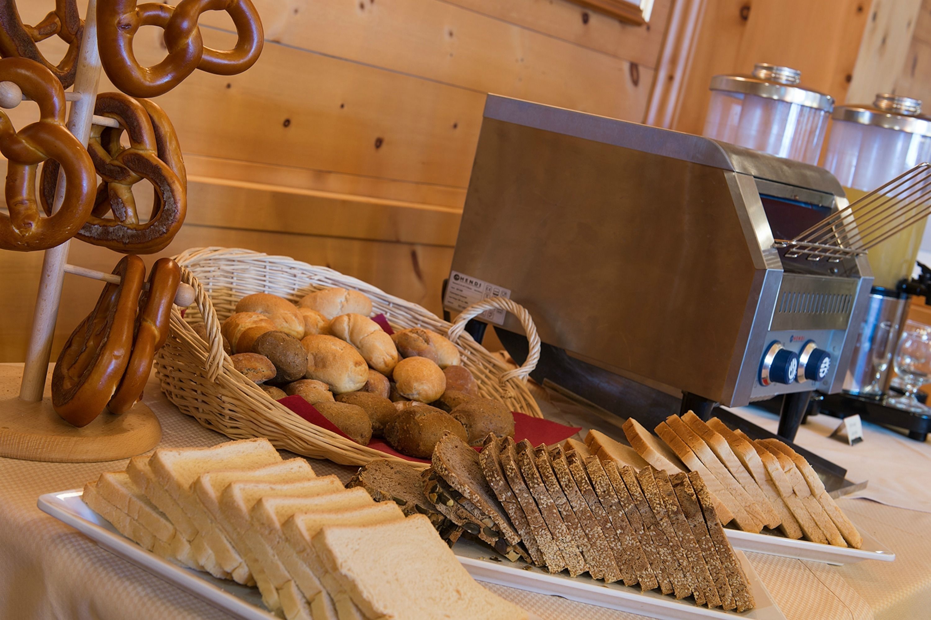 A variety of breads and pastries on a table, including pretzels, baguettes, and sliced bread.