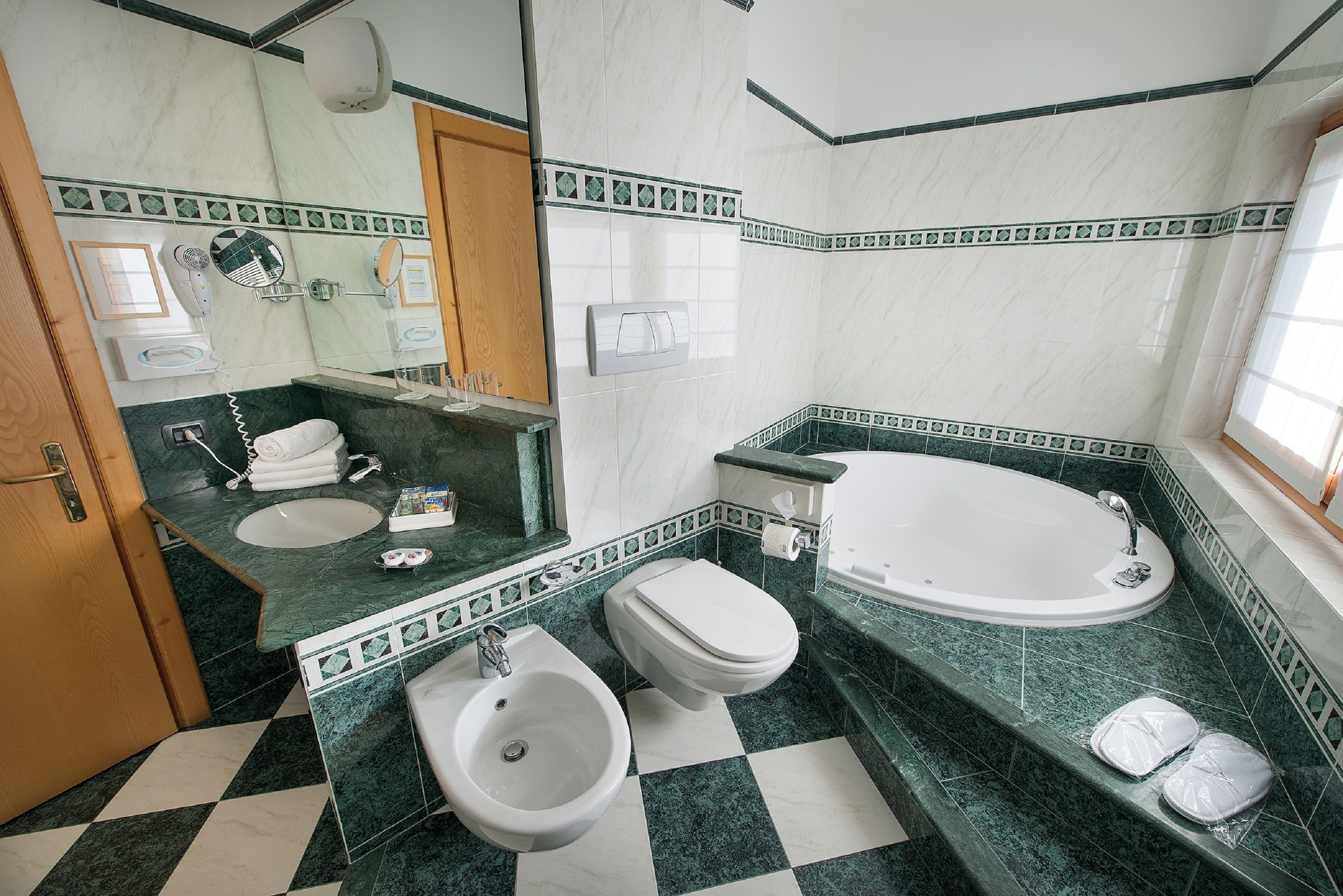Een badkamer met een hygiëneschuimer, toilet, wastafel en bad.