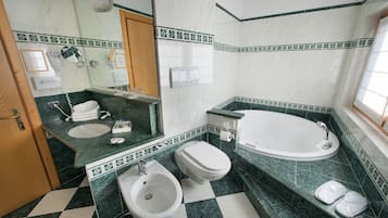 Een badkamer met een hygiëneschuimer, toilet, wastafel en bad.