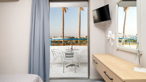 Une chambre d’hôtel avec un balcon, une télévision, un bureau et un lit.
