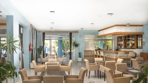 Un espace intérieur vaste et bien aménagé, avec plusieurs coins salon, un bar et des plantes en pot.