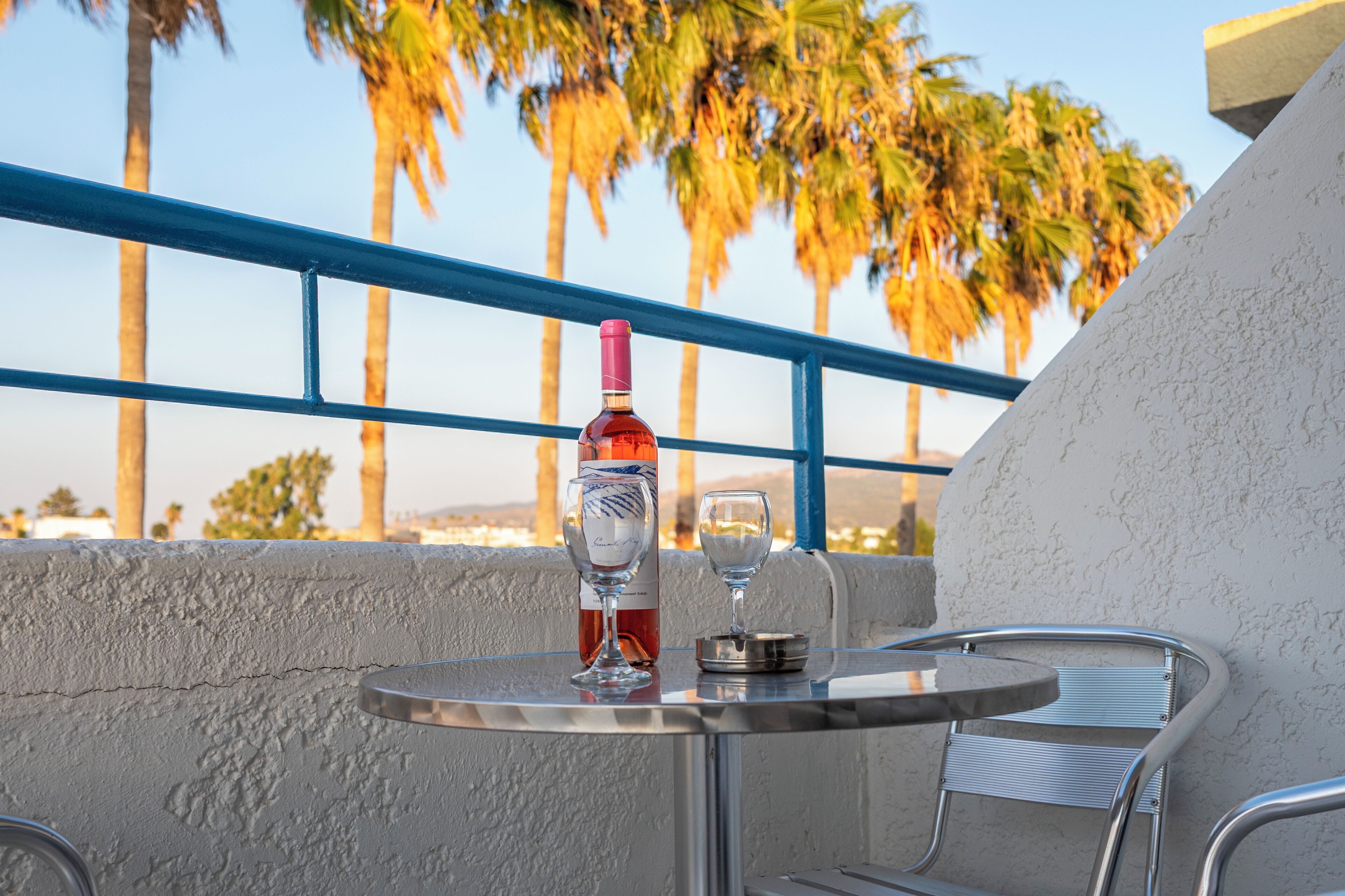 Un balcon avec une table, une bouteille de vin et un verre.