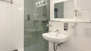 A modern bathroom with a glass-enclosed shower, a white sink, and a toilet.
