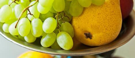 Una bandeja de frutas con uvas, peras y naranjas.