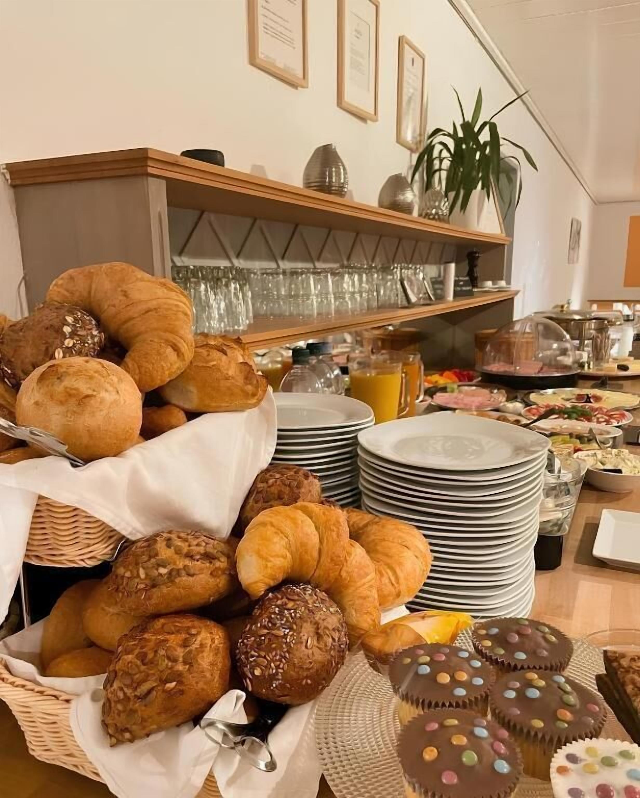 A buffet with various baked goods, including croissants and muffins, and a selection of beverages.
