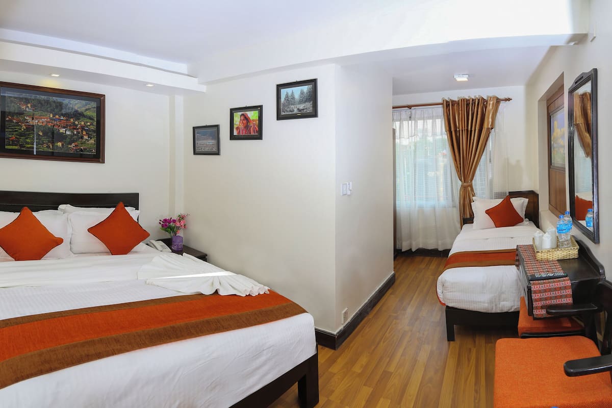 A hotel room with two beds, a desk, and a TV.