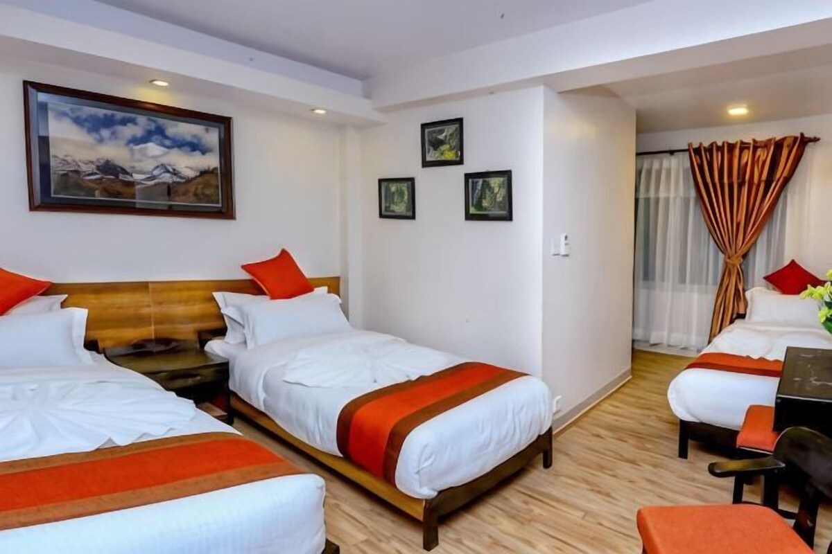 A hotel room with two beds, a desk, a chair, and a window with curtains.
