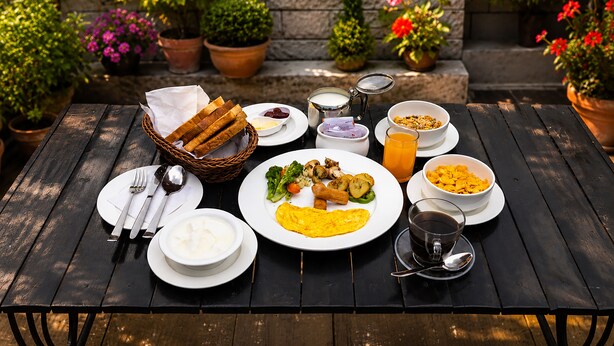 A wooden table set with breakfast items, including bread, eggs, and fruit. - Hotel Outfitter Nepal (Kathmandu)