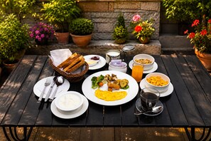 Een houten tafel gedekt met ontbijtartikelen, zoals brood, eieren en fruit.