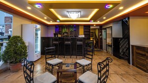 A bar area with a counter, bar stools, and a seating area with a table and chairs. - Hotel Outfitter Nepal (Kathmandu)