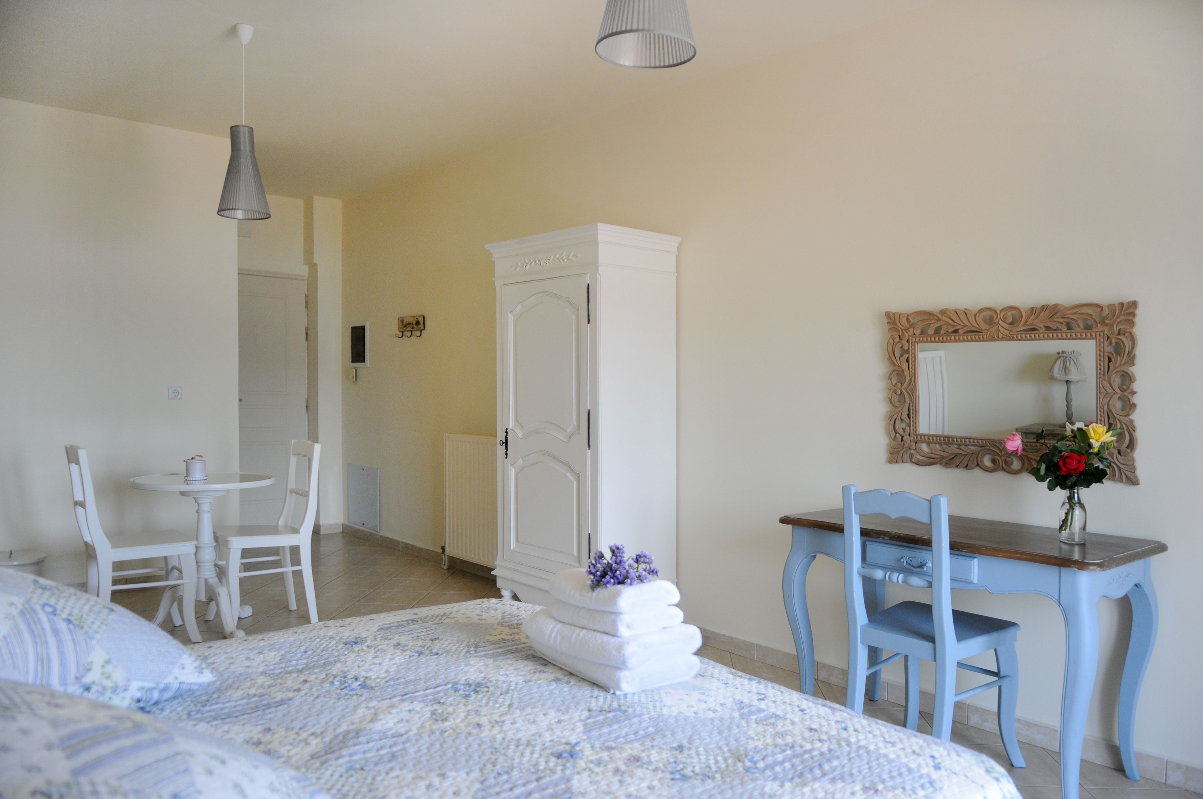 A bedroom with a bed, a desk, a chair, a wardrobe, and a mirror.