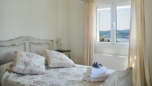 Un dormitorio con cama, mesita de noche, lámpara y ventana con cortinas.