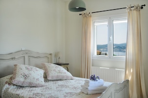 A bedroom with a bed, a nightstand, a lamp, and a window with curtains.