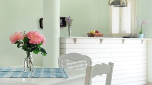 Una mesa de comedor con un jarrón de flores rosadas, un posavasos azul y una silla blanca.