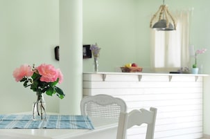 Una mesa de comedor con un jarrón de flores rosadas, un posavasos azul y una silla blanca.