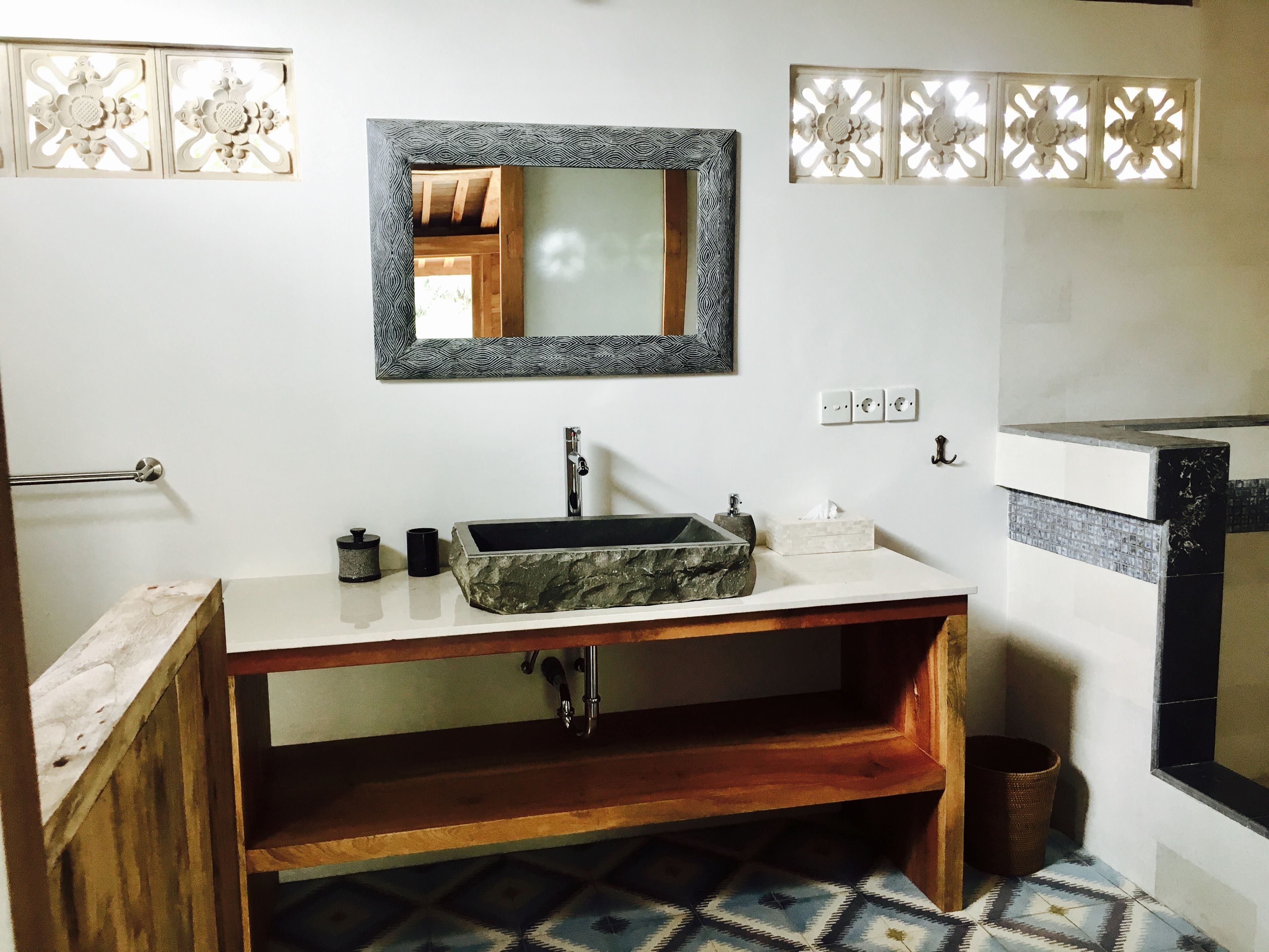 Une salle de bain avec un lavabo en pierre, un meuble-lavabo en bois et un miroir doté d’un cadre orné.