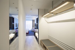 Moderni hotellihuone, jossa on suuri sänky, työpöytä, tuoli ja pieni oleskelualue.