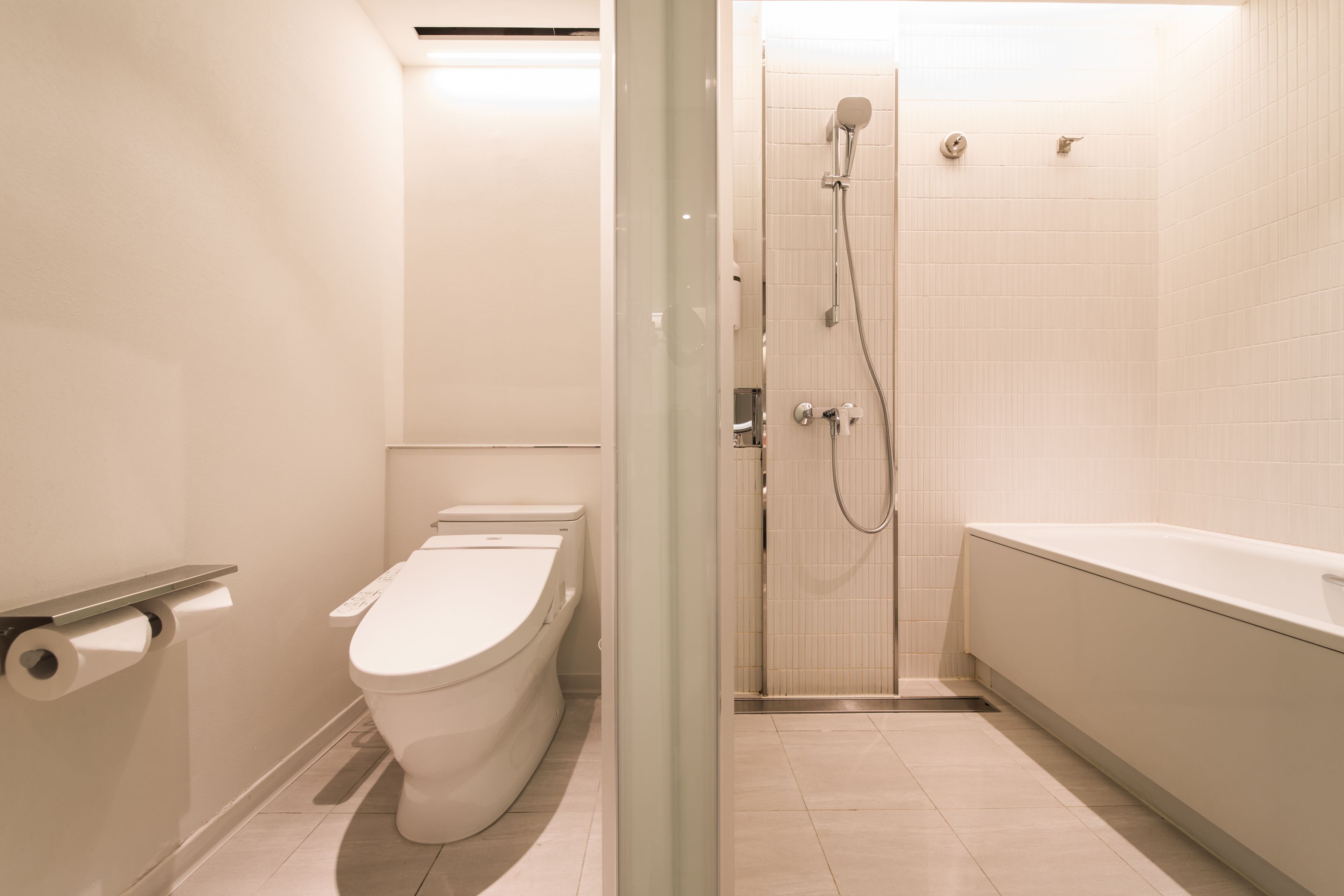 A modern bathroom with a toilet, shower, and bathtub.