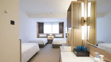 A hotel room with two beds, a large mirror, a bathroom with a sink and toiletries, and a view of the street.