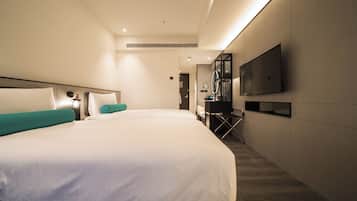 A hotel room with two beds, a TV mounted on the wall, and a desk with a chair.