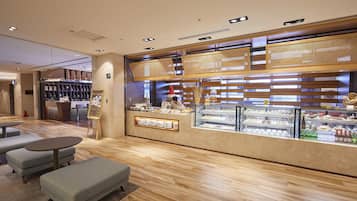 Een modern café met een houten toonbank, zitgedeelte en een vitrine vol gebak.
