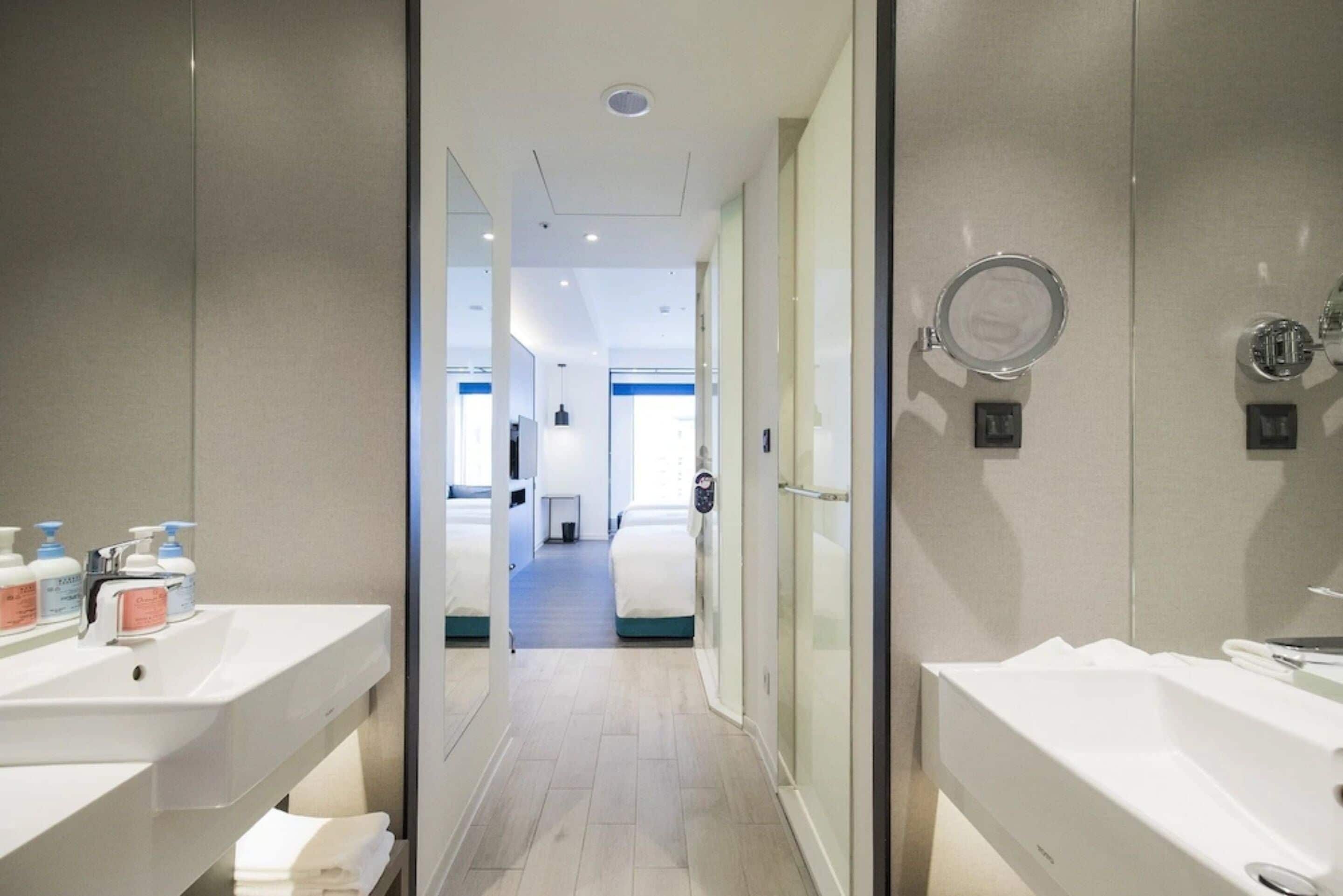 A modern bathroom with two sinks, a shower, and a glass-enclosed shower area.