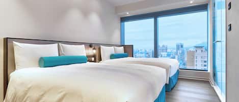 Una habitación de hotel moderna con una cama grande, una cama más pequeña y vista a la ciudad desde la ventana.