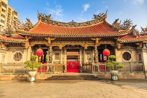 A traditional Chinese building with ornate architecture, a red gate, and potted plants. - Caesar Metro Taipei (Taipei)
