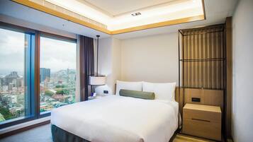 Camera d'albergo con un letto grande, un comodino, una lampada, una parete rivestita in legno e vista sulla città.