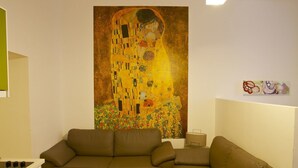 A modern living room with a large Gustav Klimt painting, a wooden floor, and a sofa. - Klimt Apartments (Vienna)