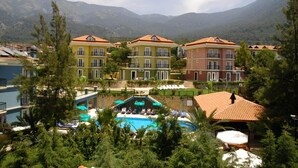A hotel with a pool, surrounded by lush greenery and mountains in the background. - Antas Deluxe Apartments (Fethiye)